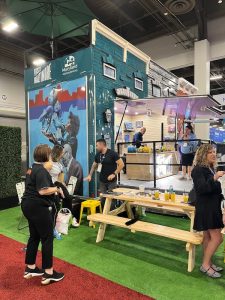 “Visit Baltimore” display with a picnic table, people chatting, and promotional materials.