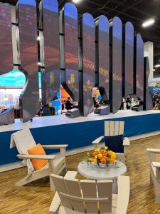 California booth with large screen, three white Adirondack chairs surrounding a low round table.
